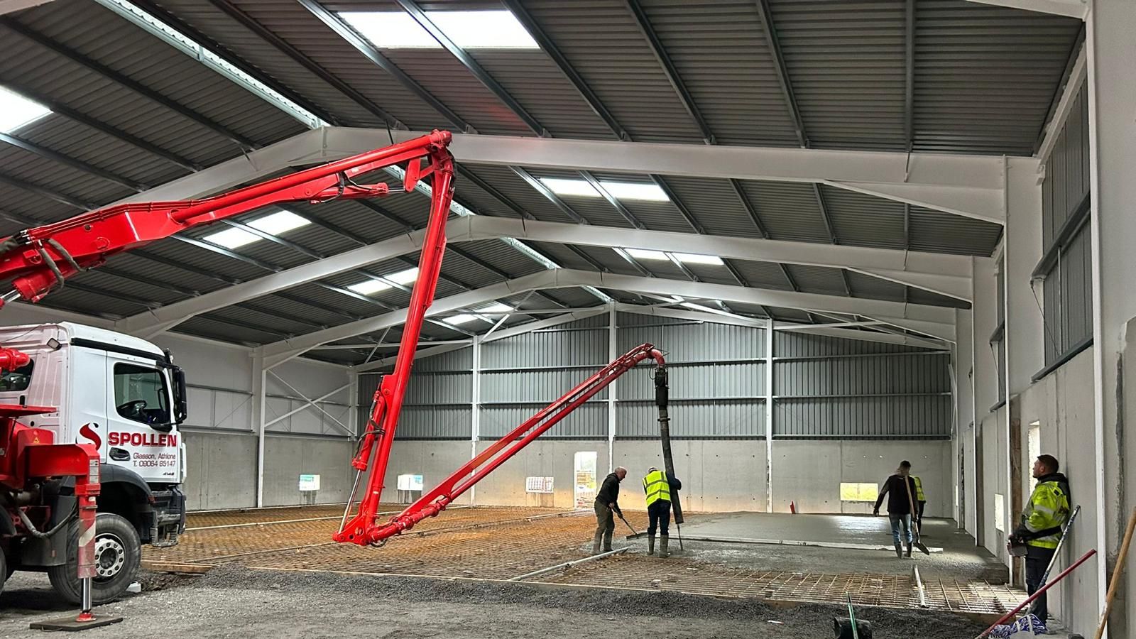The boom pump placing a floor slab inside a new steel-framed shed