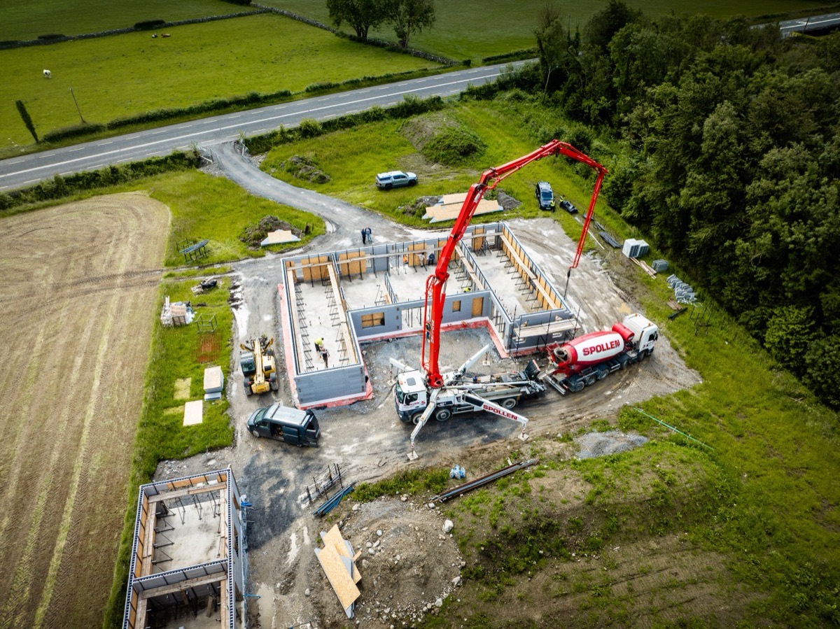 The Spollen 42m boom pump reaching across a house build from the road, with a mixer feeding it